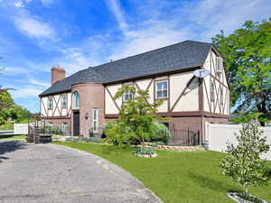 Tudor house with brick siding, a chimney, and roof with shingles