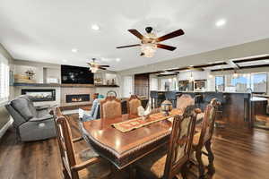 Dining space featuring healthy amount of natural light, dark wood-style flooring, a fireplace, recessed lighting, and a ceiling fan