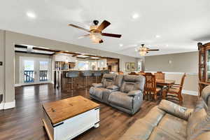 Living room featuring dark wood-type flooring, ceiling fan, recessed lighting, beam ceiling, and french doors