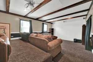 Carpeted living area with beamed ceiling and a textured ceiling