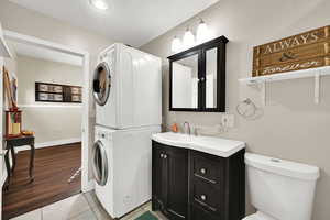 Bathroom with vanity, light tile patterned floors, estacked washer and dryer, and a textured ceiling