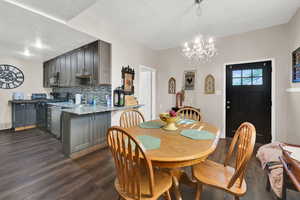 Dining space with dark wood-style floors, a textured ceiling, and a chandelier