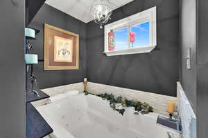 Full bath featuring a whirlpool tub, a chandelier, and a textured ceiling