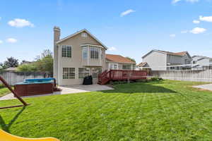 Rear view of property with hot tub and large grassy area
