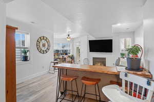Kitchen 3 with a kitchen bar, a glass covered fireplace, wood counters, light wood-style flooring, and a textured ceiling