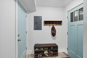 Mudroom with electric panel and light wood-type flooring