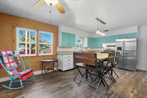 Kitchen 2 with stainless steel appliances, dark wood-type flooring, hanging light fixtures, and light stone counters