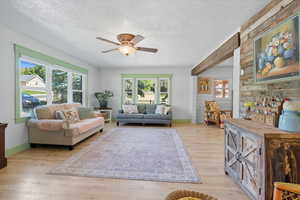 Living area with wood walls, a textured ceiling, light wood finished floors, and a ceiling fan