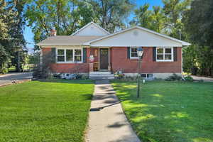 View of front of home with brick siding, a chimney, and a front yard