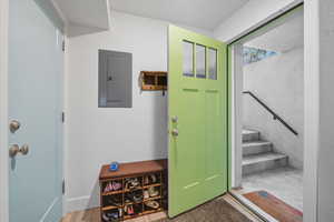 Basement Entrance foyer with electric panel, wood finished floors, and stairs