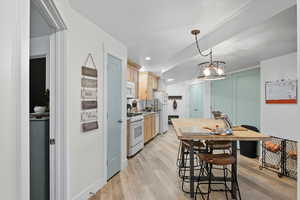 Kitchen 3 featuring light brown cabinetry, light wood-style flooring, light countertops, decorative light fixtures, and white appliances
