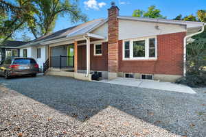 View of front of house with brick siding, a porch, and a chimney