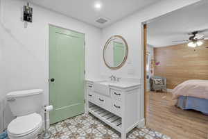Ensuite bathroom featuring wood walls, vanity, and ceiling fan