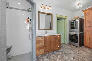 Owner's Full bathroom featuring a shower stall, vanity, and estacked washer and dryer