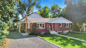 View of front of home with a front lawn, brick siding, driveway, and a chimney