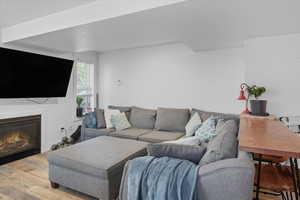 Living area 3 featuring wood finished floors, a glass covered fireplace, and a textured ceiling