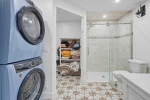 Full bath with a shower stall, vanity, and stacked washer and clothes dryer