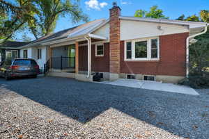 View of front of house with covered porch, brick siding, and a chimney