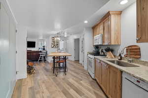 Kitchen 3 featuring light wood-style floors, white appliances, light stone countertops, a chandelier, and recessed lighting
