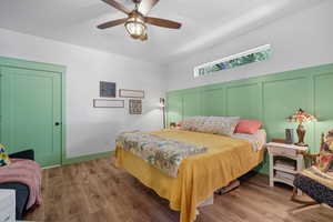 Owner's suite featuring wood finished floors, ceiling fan, and a decorative wall