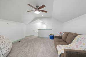 Sitting room with carpet flooring, vaulted ceiling, an upstairs landing, and ceiling fan