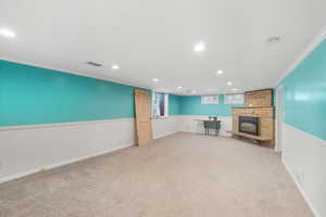 Unfurnished living room 2 with ornamental molding, light colored carpet, recessed lighting, and a stone fireplace
