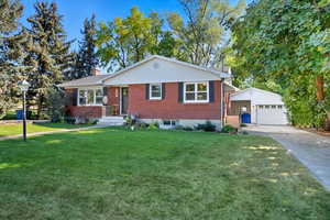 View of front of home with an outbuilding, brick siding, a front lawn, and a chimney