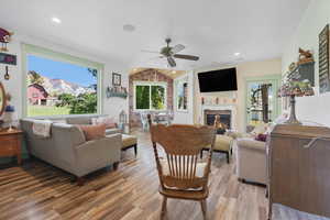 Living room with a lit fireplace, light wood finished floors, a ceiling fan, and recessed lighting