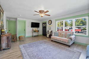 Living room featuring a textured ceiling, light wood-type flooring, and ceiling fan