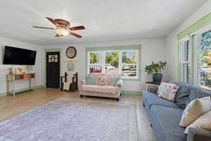 Living area with a textured ceiling, wood finished floors, and a ceiling fan