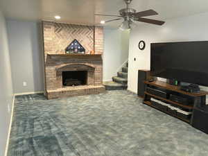 Living room featuring carpet, a fireplace, a ceiling fan, stairs, and recessed lighting