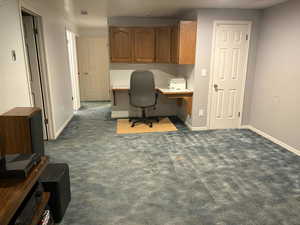 Office space with built in desk and dark carpet