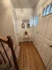 Entryway with wood finished floors, a textured ceiling, and stairway