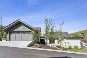 View of front of property featuring an attached garage, roof with shingles, driveway, and board and batten siding