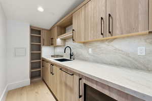 Kitchen featuring open shelves, light brown cabinetry, backsplash, light stone counters, and recessed lighting