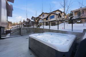 View of patio with a hot tub and a residential view