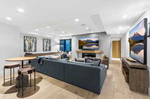 Living area with a glass covered fireplace, light wood-style flooring, and recessed lighting