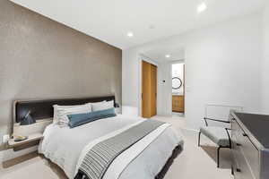 Bedroom with light colored carpet, ensuite bathroom, recessed lighting, and an accent wall