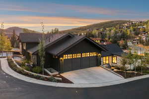 View of front facade with an attached garage, concrete driveway, a shingled roof, and a mountain view
