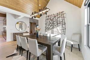 Dining area with wooden ceiling, light wood-style flooring, and vaulted ceiling