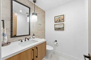 Half bathroom featuring tile walls and vanity
