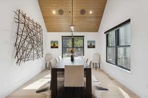 Dining area featuring wood ceiling, light wood finished floors, and high vaulted ceiling