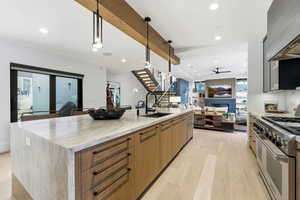 Kitchen featuring modern cabinets, double oven range, light stone counters, pendant lighting, and recessed lighting