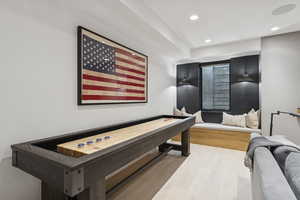 Rec room with light wood-style flooring, recessed lighting, and a raised ceiling