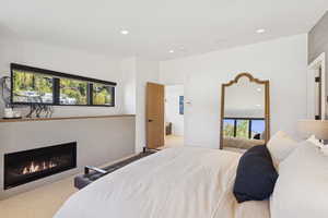Bedroom featuring recessed lighting, a glass covered fireplace, and carpet floors