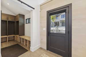 Mudroom featuring light tile patterned floors and vaulted ceiling