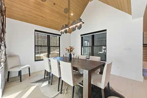 Dining space featuring wooden ceiling, high vaulted ceiling, and light wood-style flooring