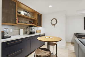 Bar featuring backsplash, light wood-style flooring, recessed lighting, open shelves, and light stone countertops