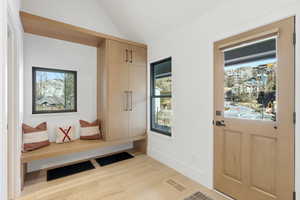 Mudroom featuring light wood finished floors and vaulted ceiling