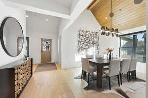 Dining room with light wood-style flooring, vaulted ceiling, recessed lighting, and a chandelier